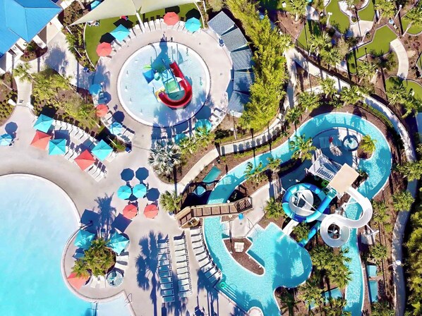 An aerial view of a resort with a central pool, multiple water slides, and sun loungers.