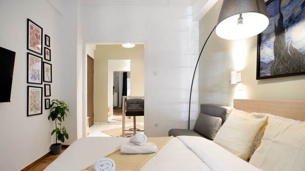 A hotel room with a bed, a desk, a chair, a lamp, and a painting on the wall. - Starry Nights - Elegent Studio in Athens (Greece - Athens)