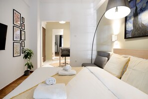 A hotel room with a bed, a desk, a chair, a lamp, and a painting on the wall. - Starry Nights - Elegant Studio in Athens (Greece - Athens)