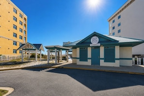 A public beach access building with a sign, a covered picnic area, and a parking lot. - Tiny Home on the Boardwalk | Walk to the Beach (Fort Walton Beach)