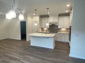A modern kitchen with white cabinetry, a central island, and pendant lighting.