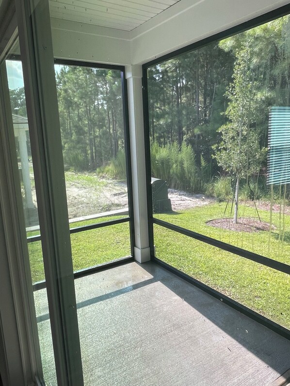 A room with large glass doors leading to a grassy outdoor area with trees.