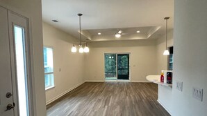 A spacious room with hardwood flooring, a large sliding glass door, and a white countertop with a sink.