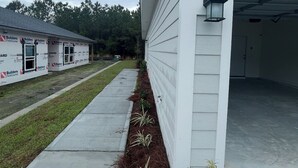 A white building with the number 78, a covered driveway, and a landscaped area with plants.