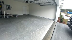 A spacious, empty garage with a concrete floor and metal roof.