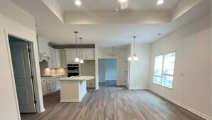 A spacious kitchen with white cabinets, a central island, and pendant lighting.