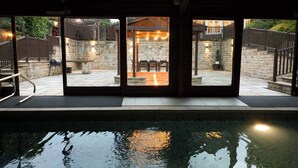 A pool area with a stone patio, outdoor seating, and a view of the backyard through large glass doors. - Habberjam Farm: Swimming Pool, Sauna, Hot Tub, Fire Pit (Marsh Lane)