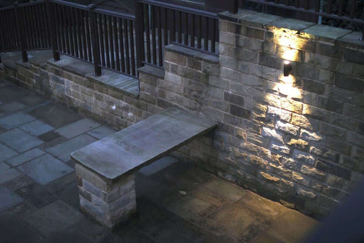 A stone bench and a wall with a light fixture.