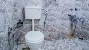Un baño con piso de mármol, inodoro blanco, ducha y ventana.