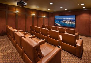 Relax in a cozy movie theater with a semi-circular row of recliner seats and a large flat-screen TV.