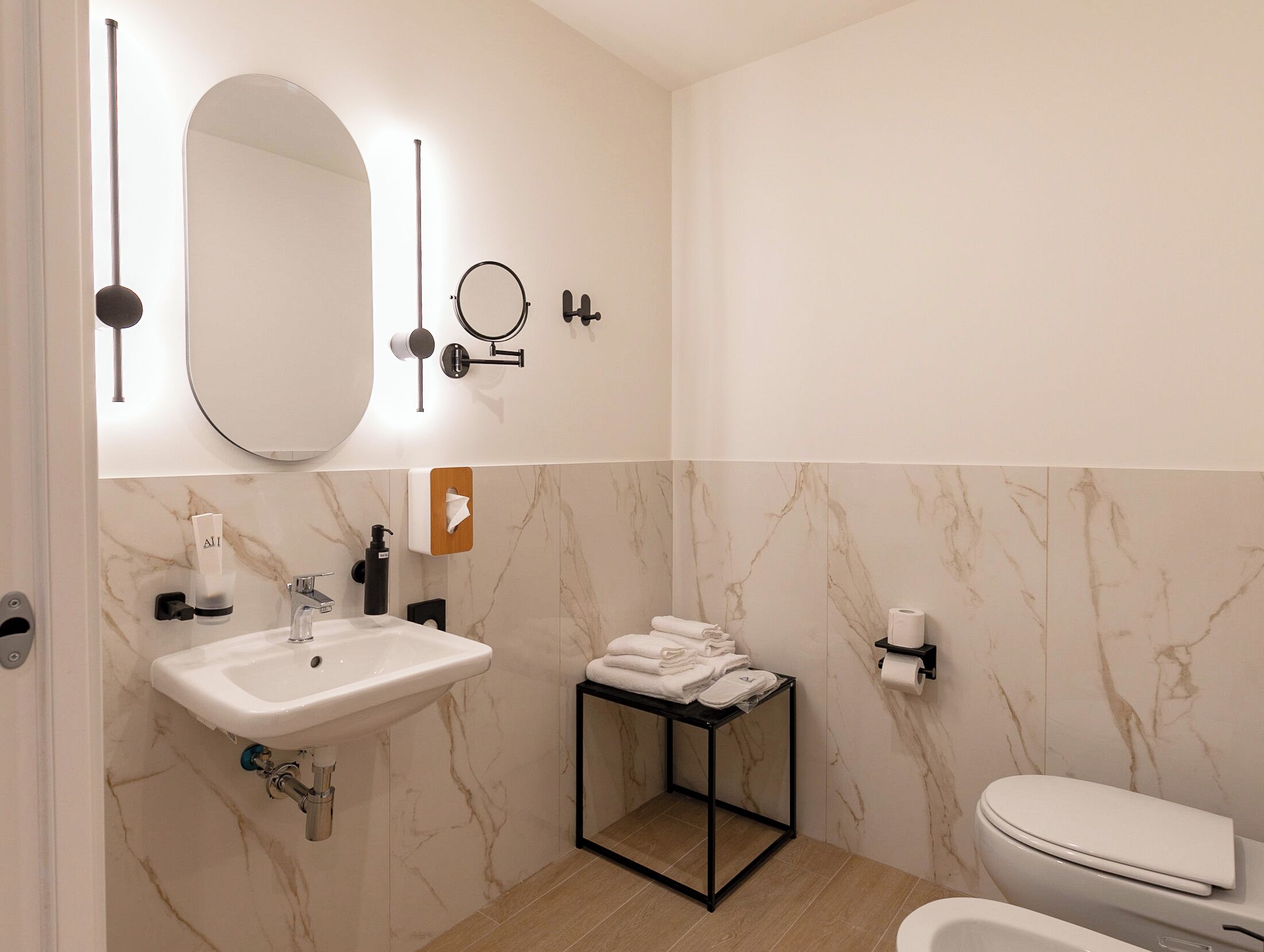 A modern bathroom with a white sink, mirror, and toilet.