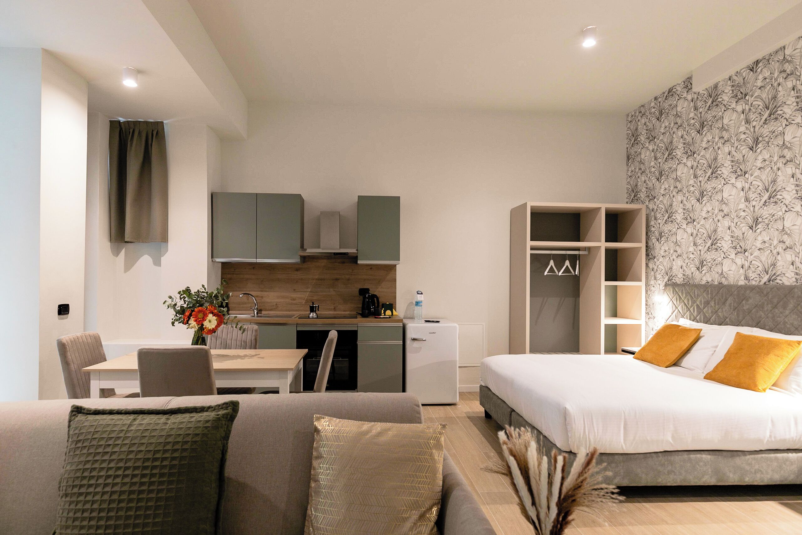Una habitació d'hotel moderna amb llit, sofà, zona de dinar i petita cuina.