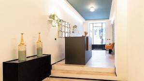 A modern interior with a black console table, decorative vases, a mirror, and a staircase leading to a dining area.