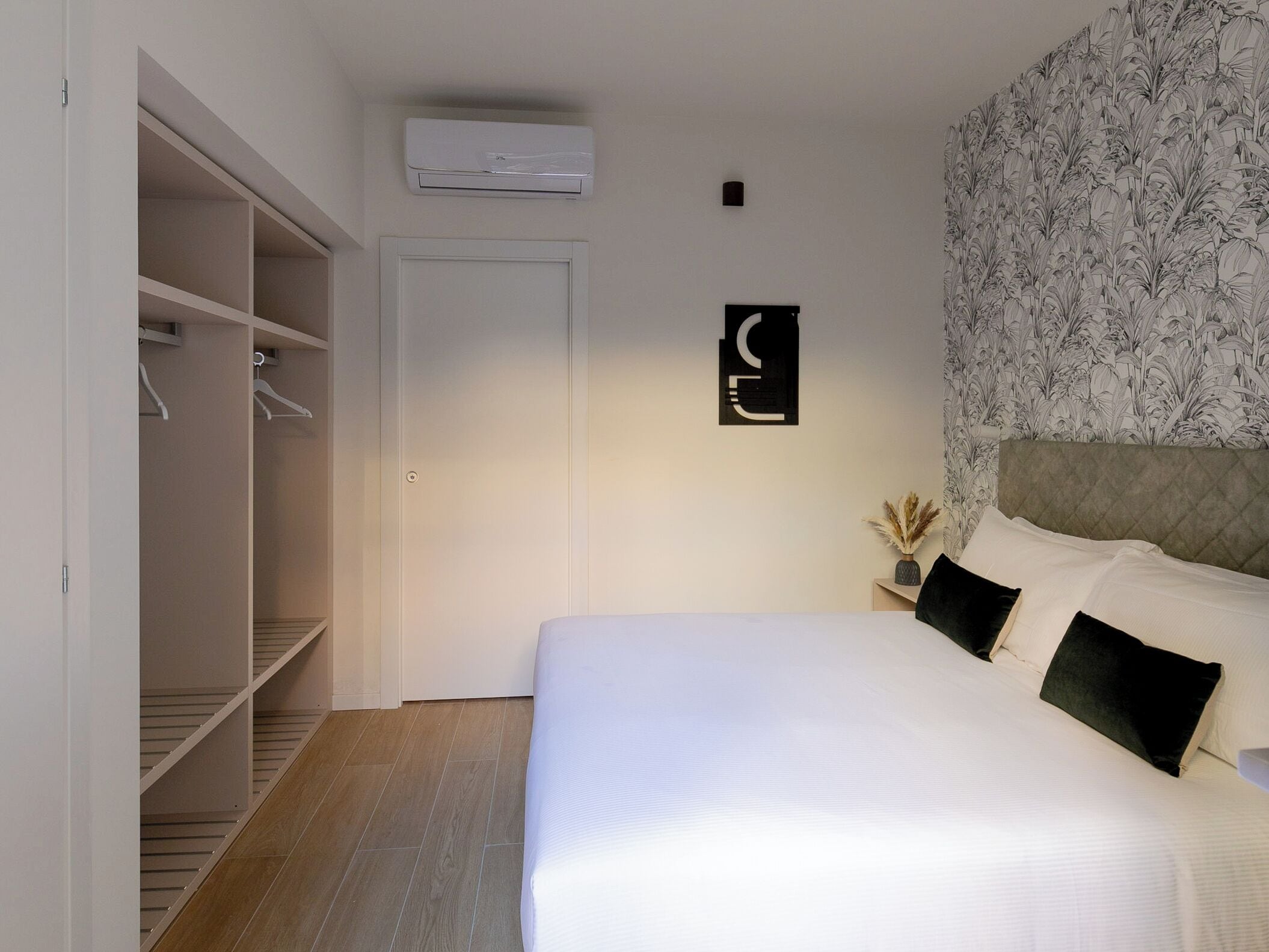Un dormitorio con cama, armario y aire acondicionado instalado en la pared.