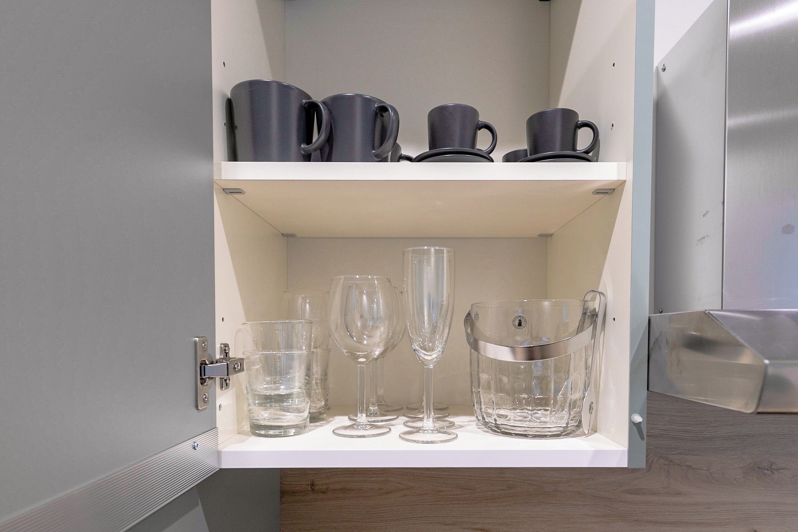 Un meuble avec des étagères contenant divers objets en verre et des tasses.