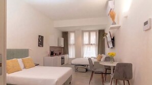 A hotel room with a bed, a desk, a chair, and a small table.
