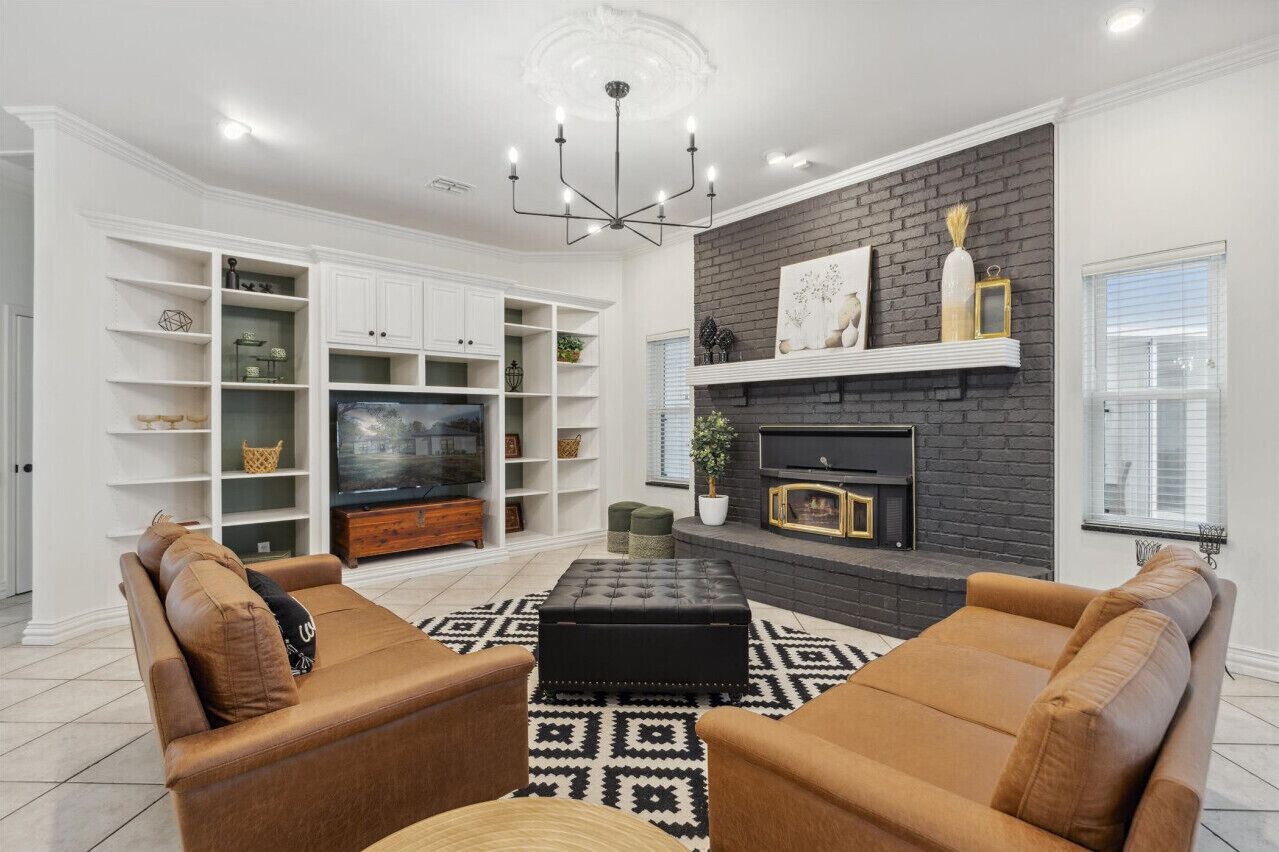 A modern living room with a fireplace, white shelving, and a large TV.