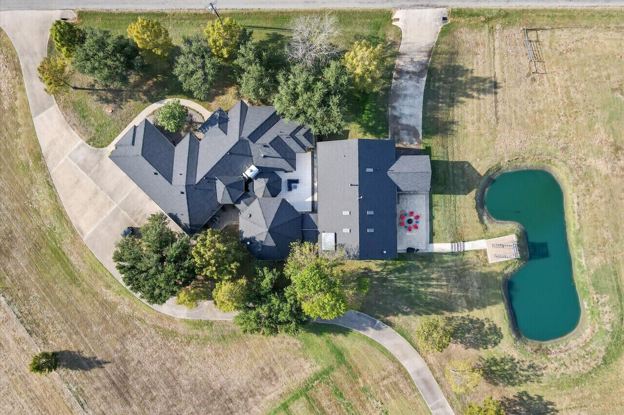 Eine Vogelperspektive eines Hauses mit einem großen Dach, einem Schwimmbad und umgebender Bepflanzung.