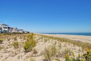 A beachfront property with a sandy beach and dune vegetation. - Coastal Retreat at Sea Del Community: 5 Bedroom Sanctuary Steps from the Beach! Dog Friendly, WIFI, Tennis, Spacious Outdoor Seating! (Bethany Beach)