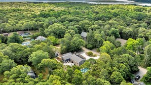 A large, secluded property with multiple houses surrounded by dense forest, a swimming pool, and a view of the ocean.