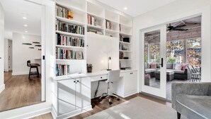 A modern living room with a built-in bookshelf, a desk, and a comfortable seating area with a view of the outdoors.