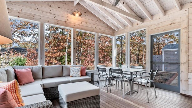 A covered patio with a sofa, chairs, and a table.