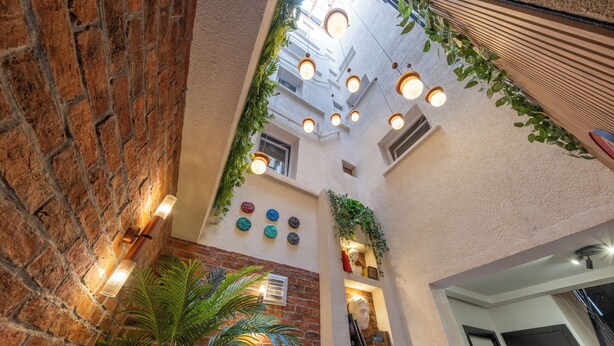 A multi-level atrium with brick walls, hanging plants, and pendant lighting. - Hexa Apartments Sisli  (Istanbul)