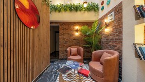 A modern lobby with a brick wall, two leather armchairs, a glass coffee table with magazines, and a wooden wall with vertical slats. - Hexa Apartments Sisli  (Istanbul)