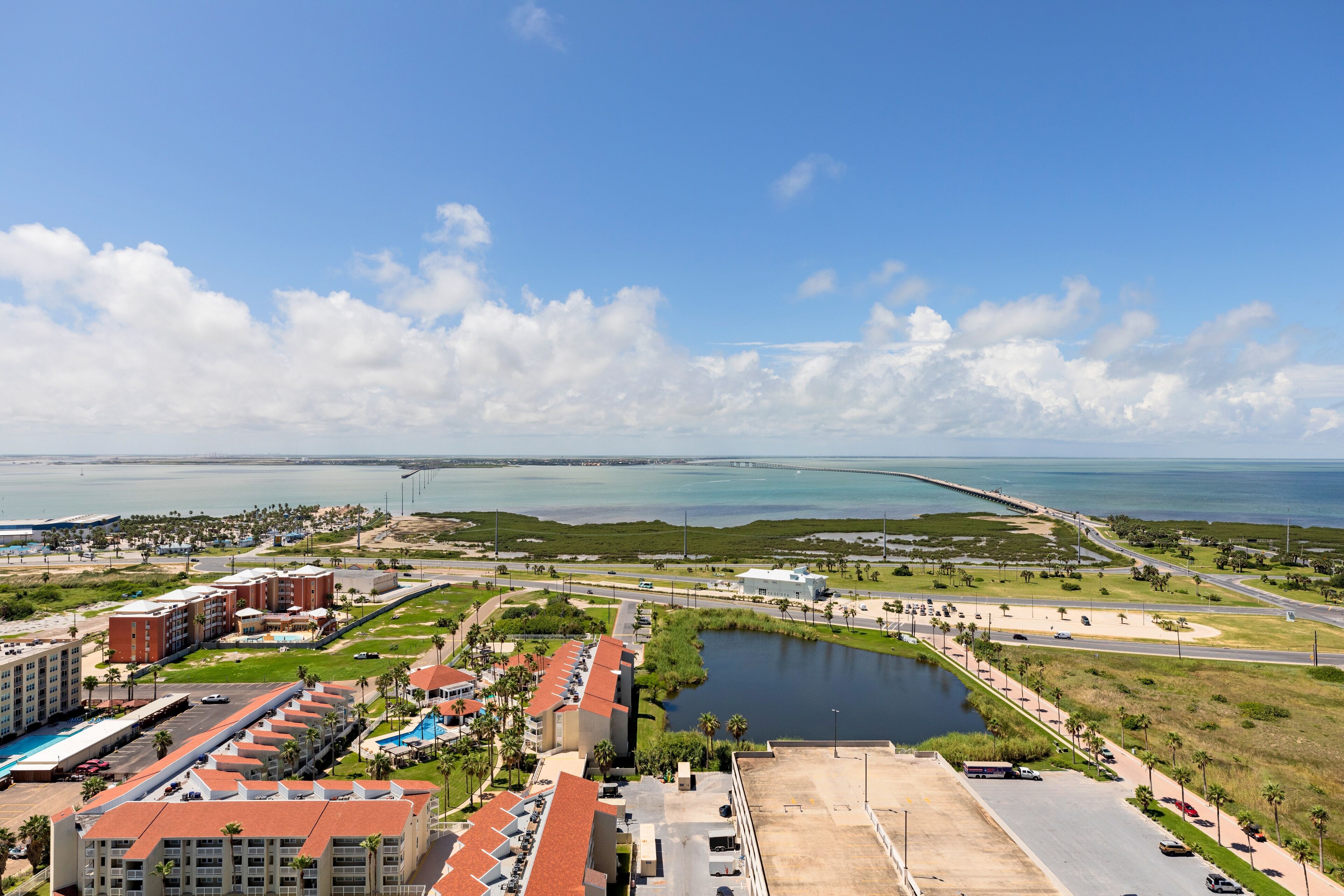 Un hotel costero con varias edificaciones, un puerto deportivo y un puente al fondo.