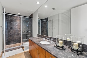 Un baño moderno con cabina de ducha de vidrio, un lavamanos blanco y un espejo grande.