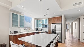 A modern kitchen with a large island, wooden cabinets, and stainless steel appliances. - Sapphire Condo & Spa Unit # 2106 3 Bedroom Condo (South Padre Island)