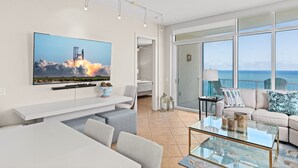 A modern living room with a large flat-screen TV, a glass coffee table, and a sofa. - Sapphire Condo & Spa Unit # 2106 3 Bedroom Condo (South Padre Island)