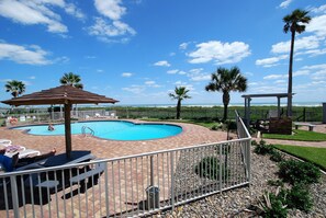 Relax by the pool surrounded by lush greenery and a gazebo.