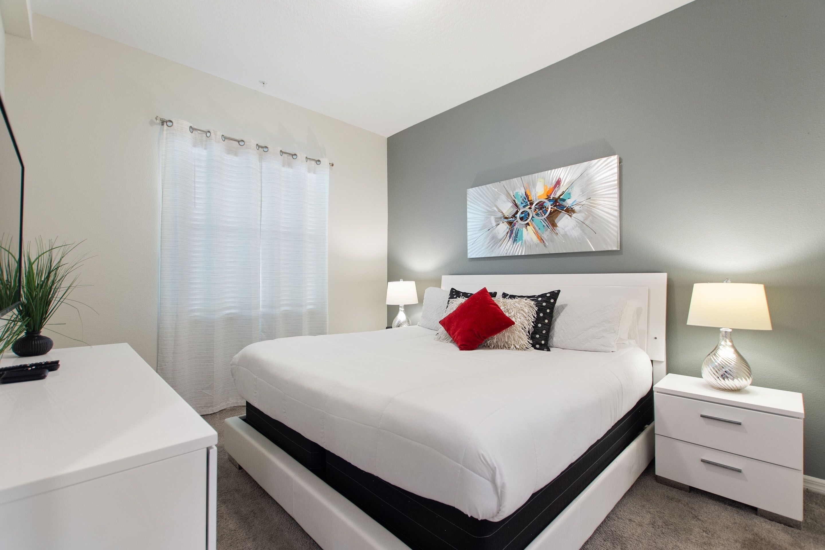 Une chambre à coucher bien rangée, avec un lit, des tables de chevet, une lampe et un élément décoratif mural.