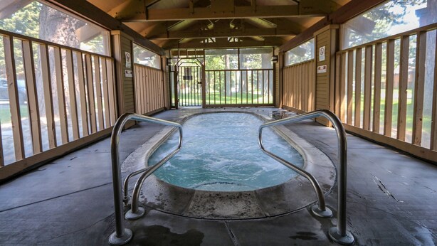 Ein Whirlpool im Innenbereich mit Metallgeländern, einem Betonboden und einer Holzzahl.