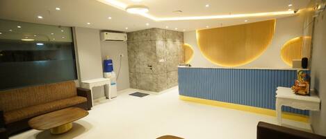 Un moderno vestíbulo de hotel con un sofá, una recepción y un diseño de pared azul y amarillo.