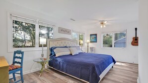 Een slaapkamer met een bed, een stoel, een tafel en een gitaar.