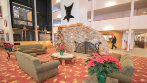 Eine großzügige Lobby mit Kamin aus Stein, bequemen Sitzgelegenheiten und einem Weihnachtsbaum.