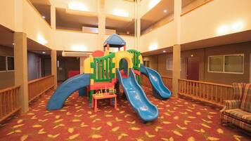 A children's play area with slides and climbing structures in a hotel lobby.