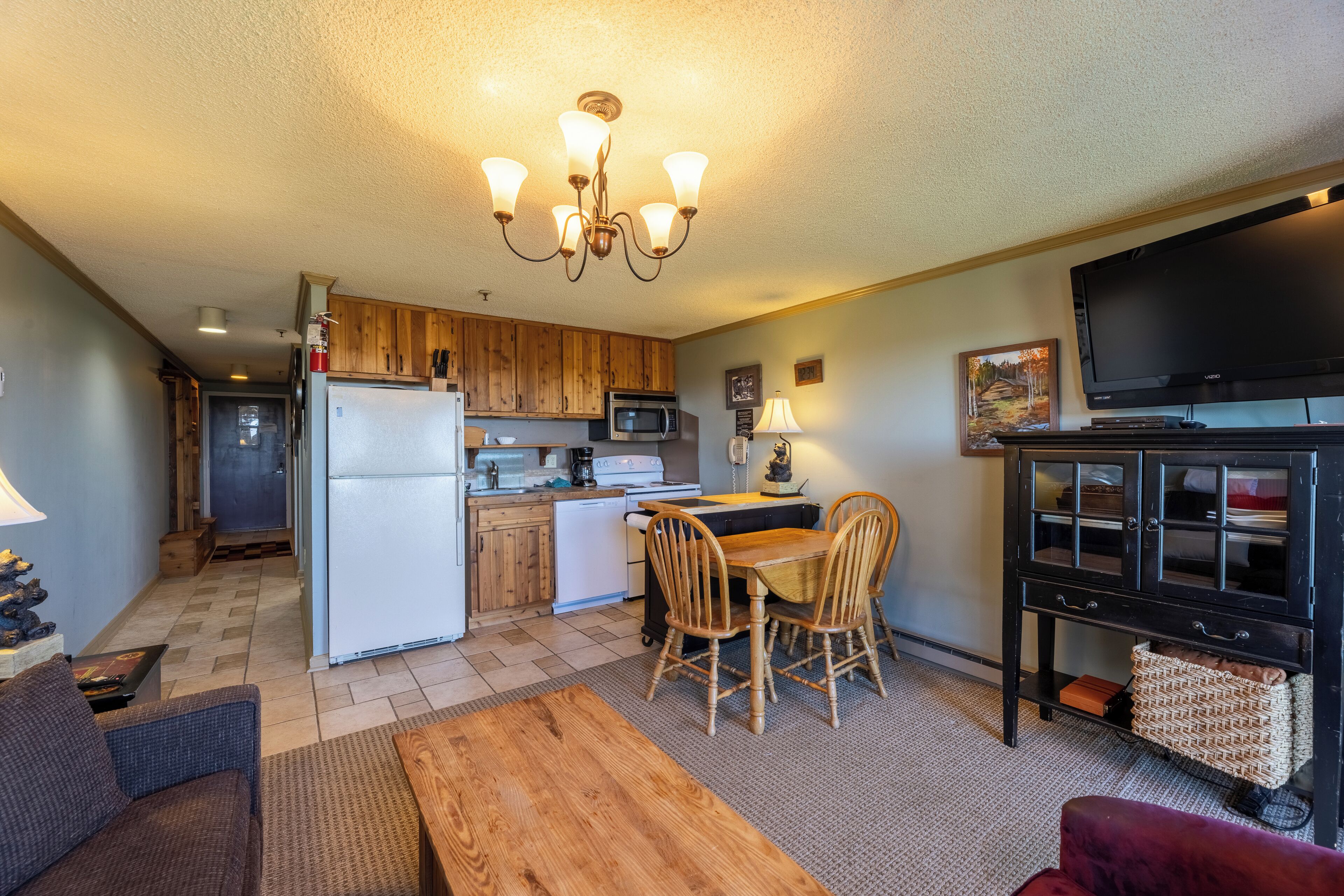 A compact kitchen with wooden cabinets, a microwave, and a dining area with a table and chairs.