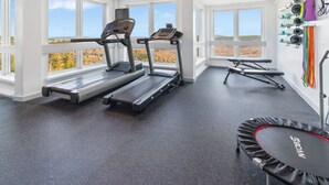 Ein Fitnessstudio mit Laufbändern, einer Trampolin und Trainingsgeräten.
