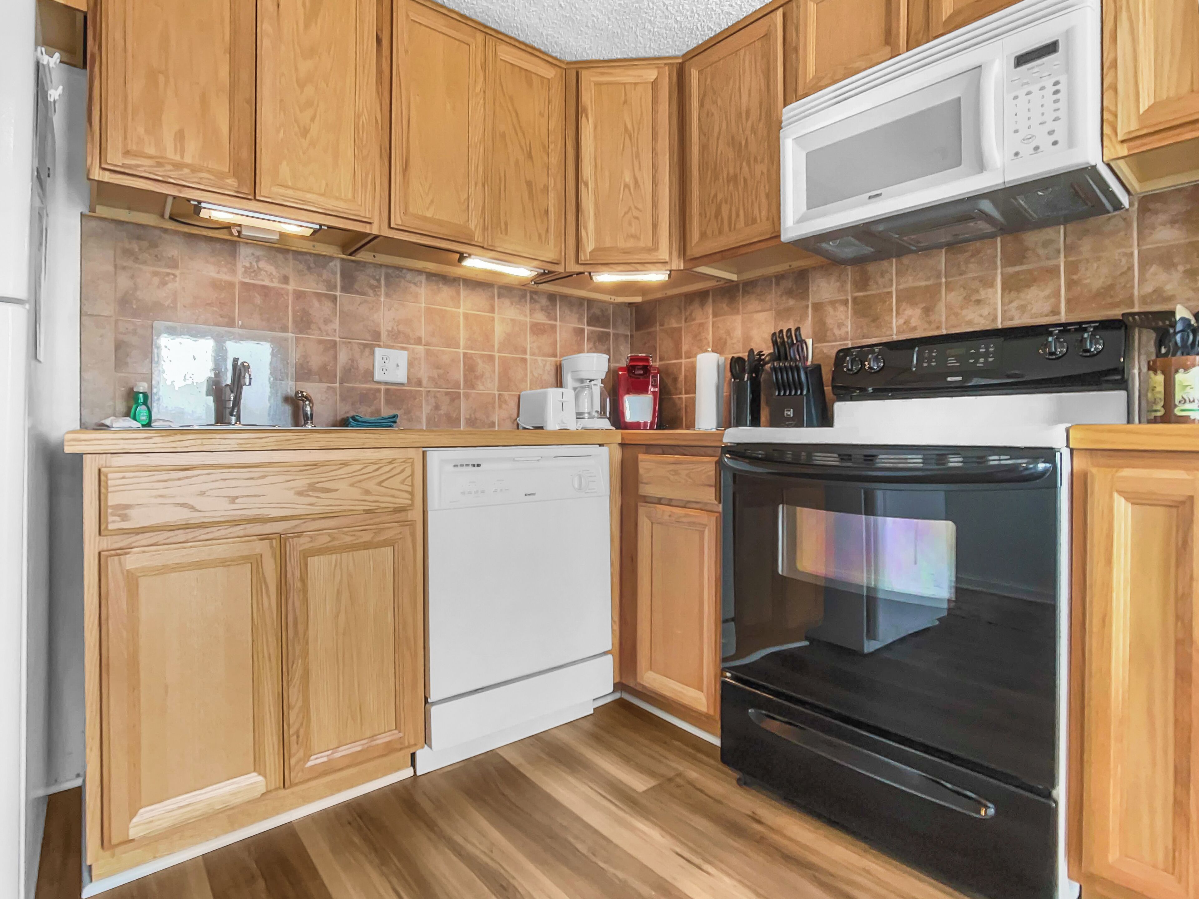 A kitchen with wooden cabinets, a dishwasher, a stove, and a microwave.