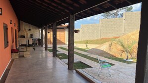 Un espacio al aire libre cubierto con suelo de piedra, pared de ladrillo y un pequeño jardín con una silla.