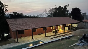 Una casa con un porche techado, piscina y un pequeño jardín.