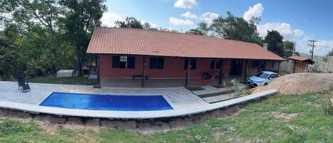 A house with a tiled roof, a swimming pool, and a hammock.