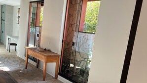 Un interior moderno con suelo de piedra, una mesa de madera y grandes puertas de cristal con diseño de piedra.