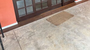 Puerta corrediza de vidrio con marco oscuro que da a un patio de concreto con felpudo.