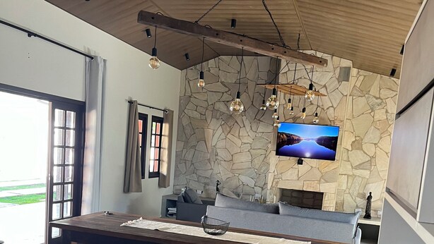 Una cocina moderna con pared de piedra, techo de madera y televisor montado en la pared.