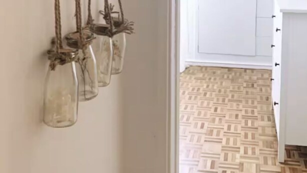 Une décoration rustique à fixer au mur, agrémentée de bouteilles en verre suspendues.