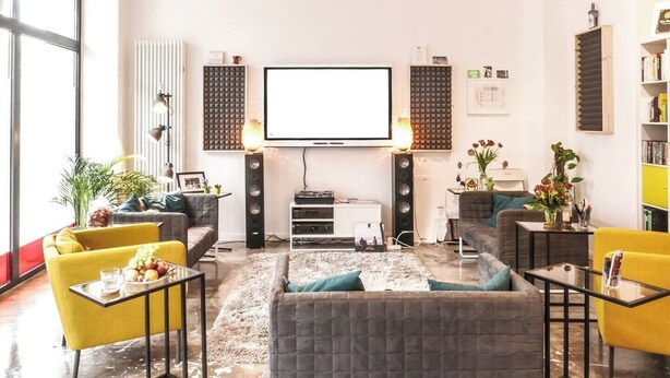 A modern living room with a large flat-screen TV, comfortable seating, and a bookshelf.